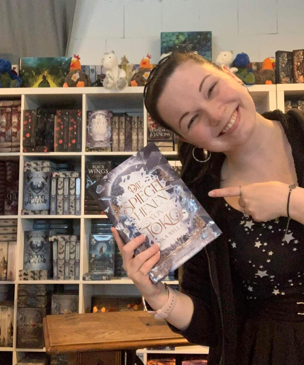 Nika hält das erste Mal beim Drachenmond Verlag ein Exemplar von "Die Spiegelhexen von Tokio" in der Hand.