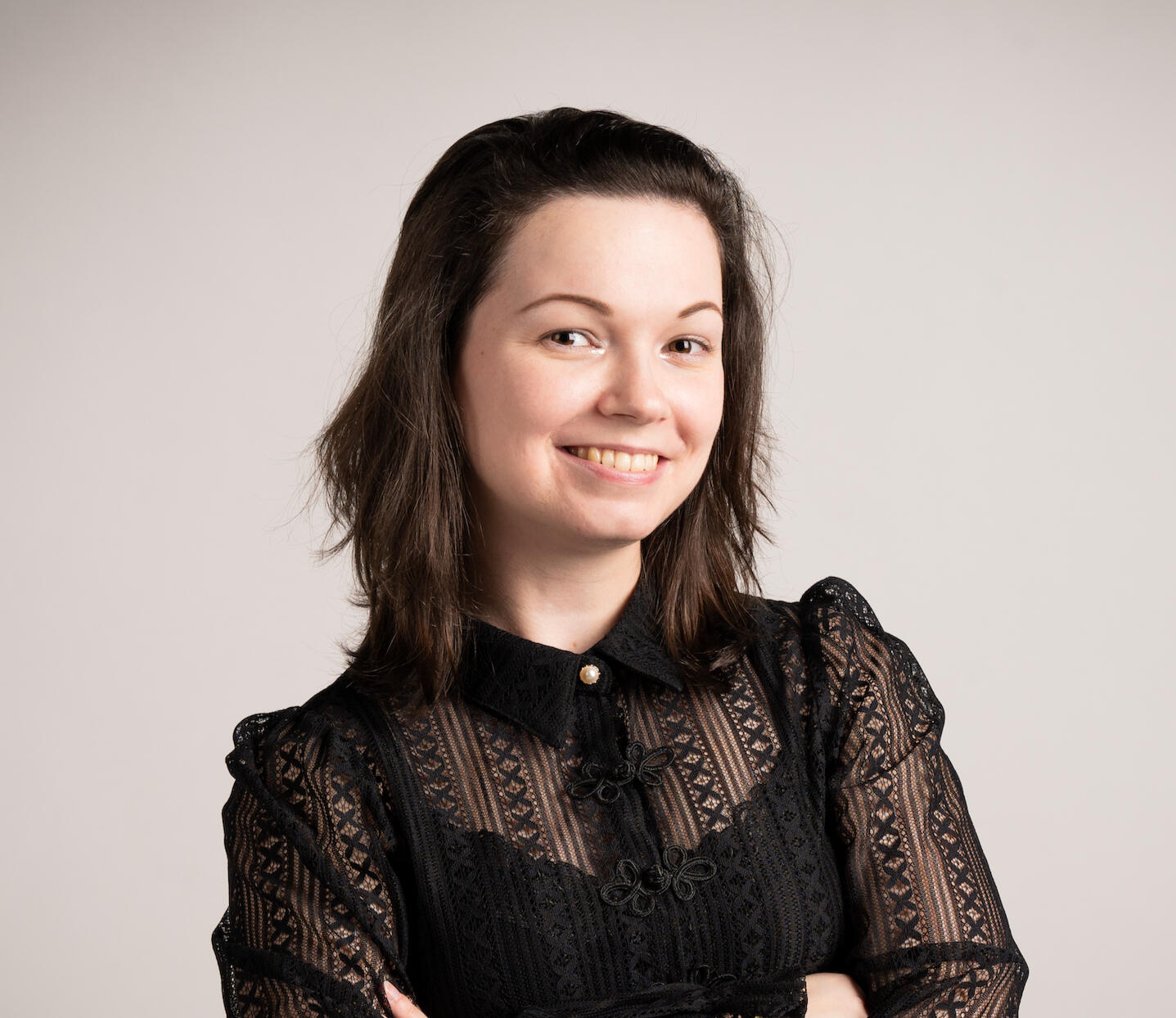 Nika Nylea lächelnd vor einer weiß-grauen Wand